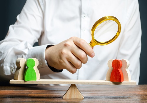 A man with a magnifying glass is looking at the rival red and green figures groups on scales. Research argument of each side. conflict resolution and the search for a compromise in the dispute.